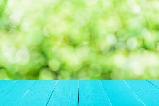 Pastel blue wooden table and blur nature tree green background with spring or summer.