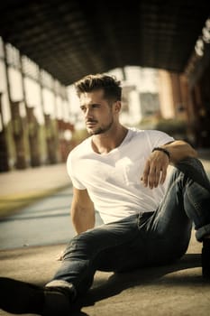 Attractive man in urban setting under big metal structure, a former industrial site