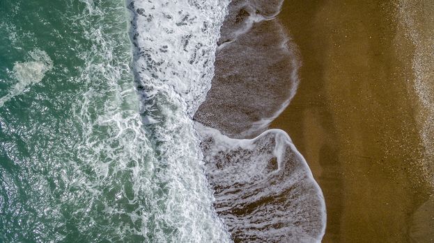 Aerial view waves break on white sand beach. Sea waves on the beautiful beach aerial view drone