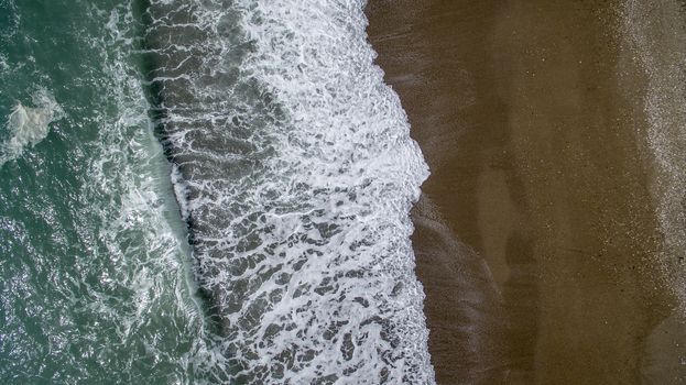 Aerial view waves break on white sand beach. Sea waves on the beautiful beach aerial view drone