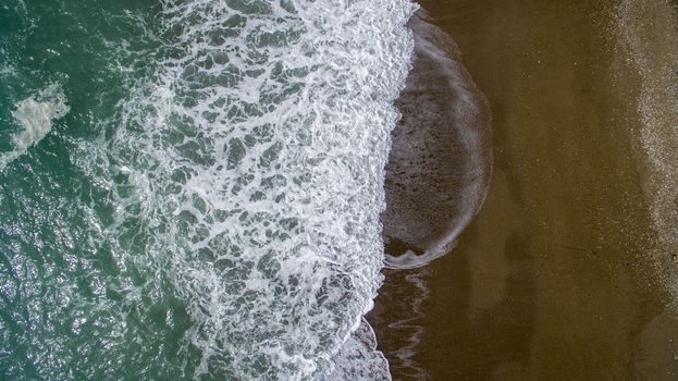 Aerial view waves break on white sand beach. Sea waves on the beautiful beach aerial view drone