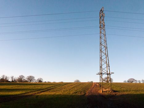 large metal tower field farm blue sky electric pylon communication power supply background; essex; england; uk