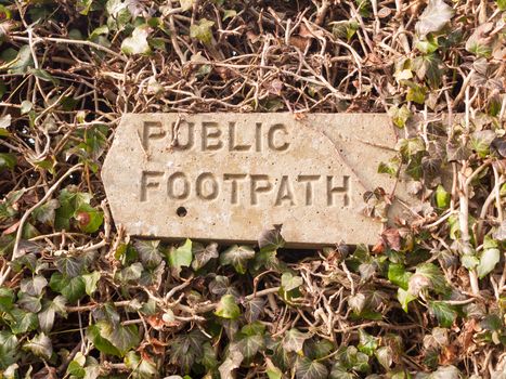 public footpath sign post stone in hedgerow direction pointer; essex; england; uk