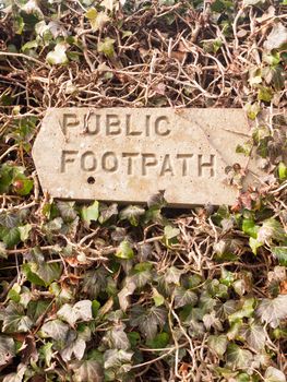 public footpath sign post stone in hedgerow direction pointer; essex; england; uk