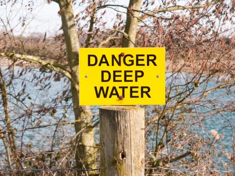 yellow and black sign danger deep water lake; essex; england; uk