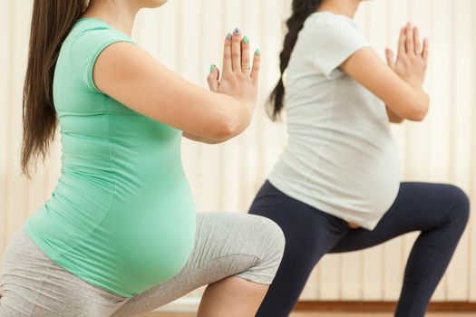 Beautiful pregnant women doing yoga in the gym