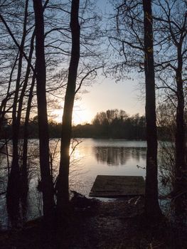 small pontoon of lake water surface with trees and sunset; essex; england; uk