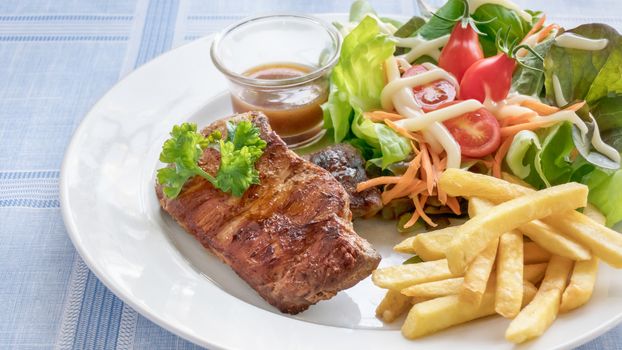 Grilled steak with french fries and fresh vegetables on white plate