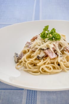 Spaghetti carbonara with bacon, mushroom and cheese on white dish