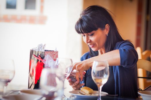 Pretty Italian Woman Enjoys Opening Gift From Friends on Patio Restaurant