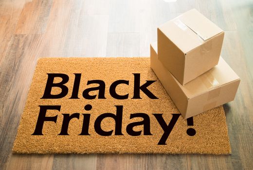Black Friday Welcome Mat On Wood Floor With Shipment of Boxes.