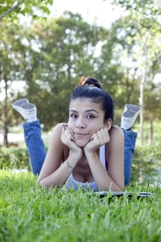 Jolly beautiful teenage girl sitting on grass.