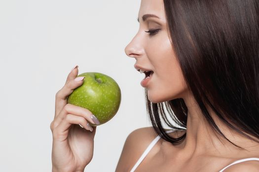 Attractive smiling woman portrait on white background with apple.