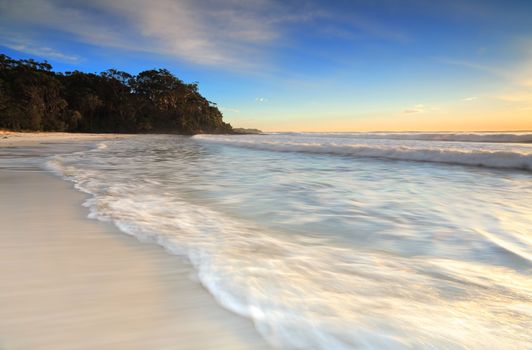 Soft motion in the waves as they ebb and flow onto the shore in early morning light.