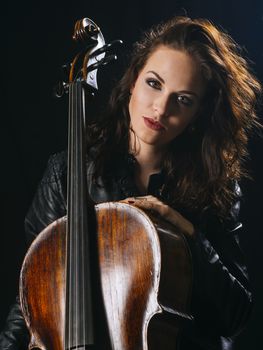 Photo of a beautiful woman posing with her old cello.