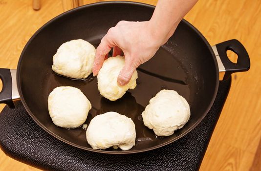 The woman lays the formed patties into the pan for further baking.