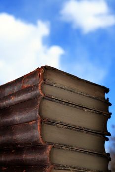 Stack of old books on blue sky background with free space