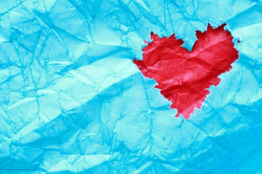 Ragged red heart made from paper on blue background