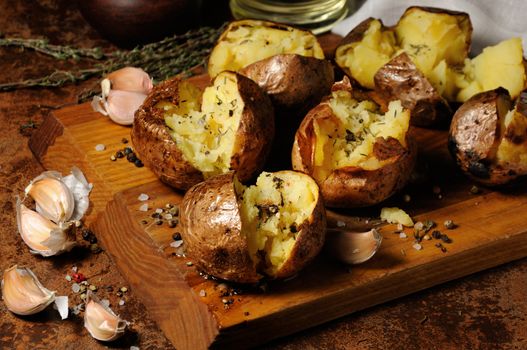 broken baked potato with spices and herbs on a wooden board