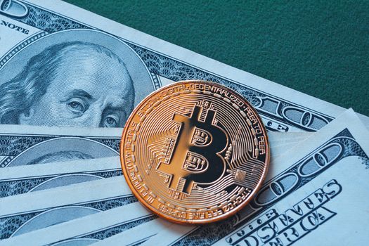 Gold Bitcoin on hundred dollars bill macro shot.