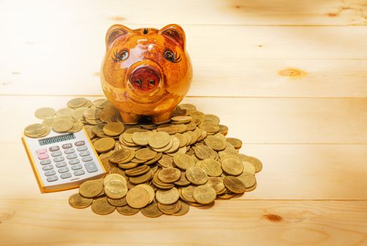 Stack coins, calculator and piggy bank on wood table and copy space