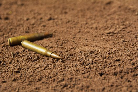 Two bullets, machine gun bullets on soil background