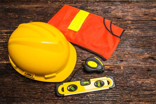 Construction tools or safety equipment with yellow helmet on wooden table.