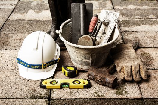 Construction tools or safety equipment with white helmet on brick ground