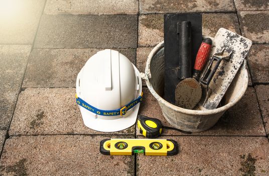 Construction tools or safety equipment with white helmet on brick ground