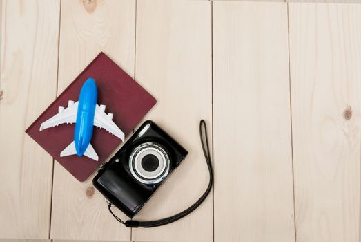 Camera with air plane and notebook for travel wooden table background. Top view with copy space.