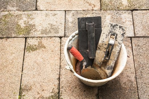 Construction tools or construction equipment with bucket on brick ground