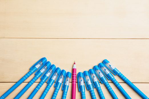 pens or writing tools on wooden table and red pen middle among blue top view