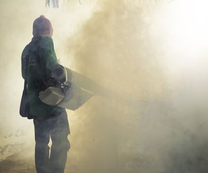 Man work fogging to eliminate mosquito for preventing spread dengue fever in Thailand.