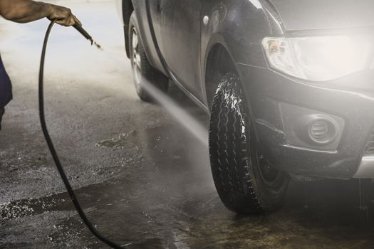 Washing black car by high pressure water. Car wash closeup. 