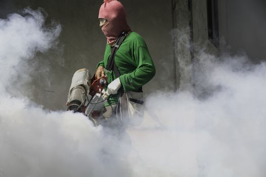 Man work fogging to eliminate mosquito for preventing spread dengue fever in Thailand.