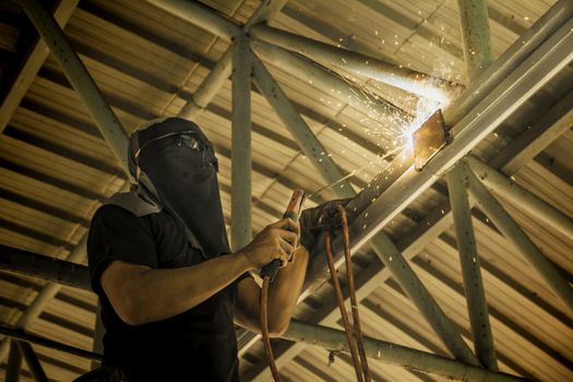 Industrial Worker at the factory steel welding under the roof.