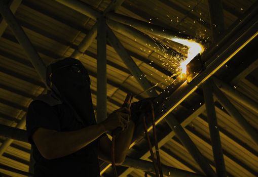 Industrial Worker at the factory steel welding under the roof.