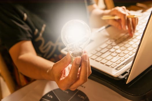 Innovation or creative concept of hand hold a light bulb with laptop.