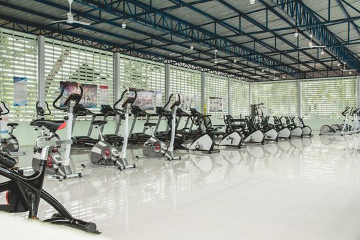 White gym interior with equipment. Fitness gym with training exercise bikes.