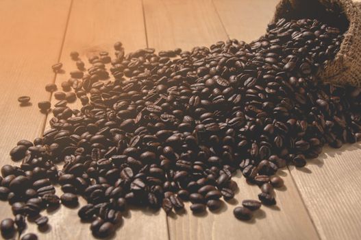 Coffee beans with sack bag on wooden table background.
