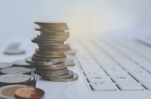 stack coins on white laptop, computer. Financial and saving concept.