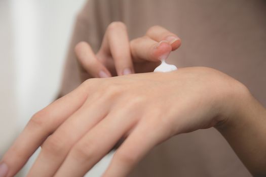 hand of woman apply lotion on skin of back hand.