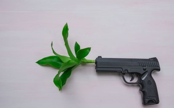 Handgun on wooden background with plant.War and peace full with hand gun.