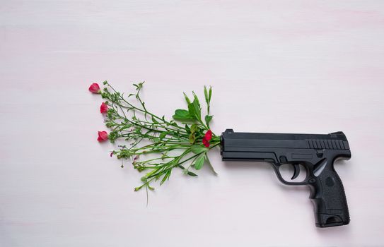 Handgun on wooden background with flowers.War and peace full with hand gun.
