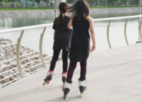 Blurred young people playing roller skates outdoor in park. Teenage girls on roller skates at outdoor.