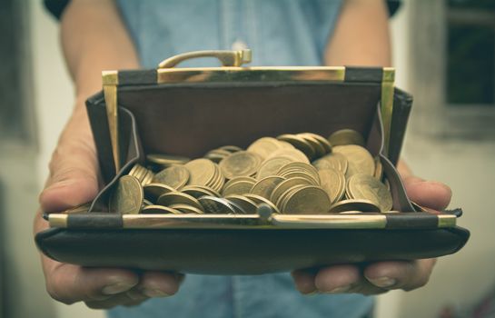 Male holding wallet with money gold coins in her hand for financial and saving money concept.