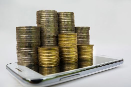 Saving money concept and money coin stack on smart-phone growing for business.