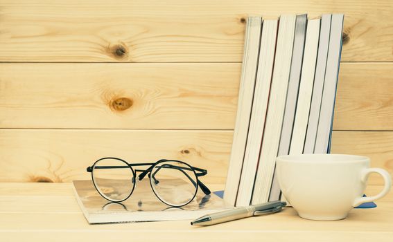 Books with glasses above. Book with glasses and coffee cup on table and wooden background concept for education.