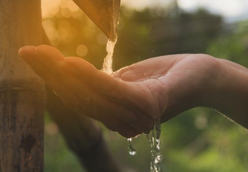 Water pouring in woman hand on nature background.