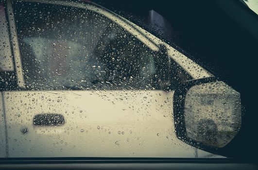 Water drop on glass mirror of car with white car.